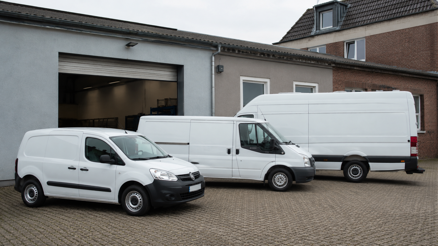 Drei Transporter unterschiedlicher Größe auf einem Hof